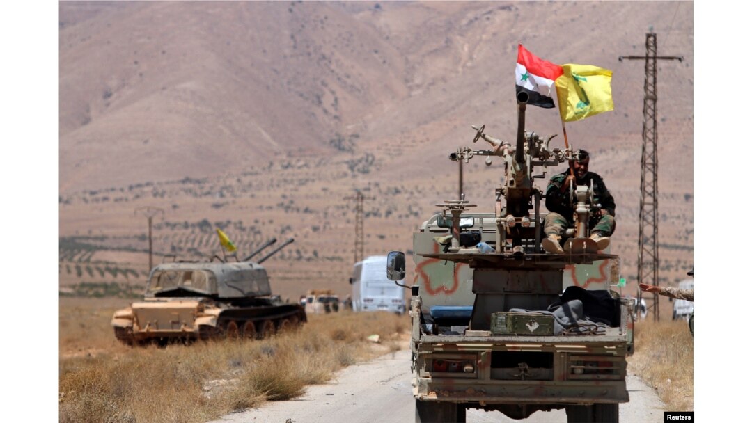 FILE - Hezbollah and Syrian flags flutter on a military vehicle in Western Qalamoun, Syria, Aug, 28, 2017.