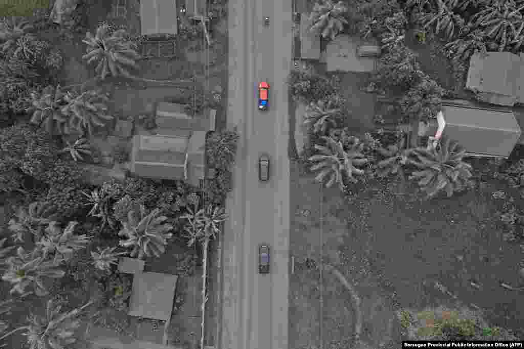 Vehicles drive past ash-covered houses and vegetation in Juban town, Sorsogon province, Philippines, after Bulusan volcano erupted sending a plume of ash over the area.