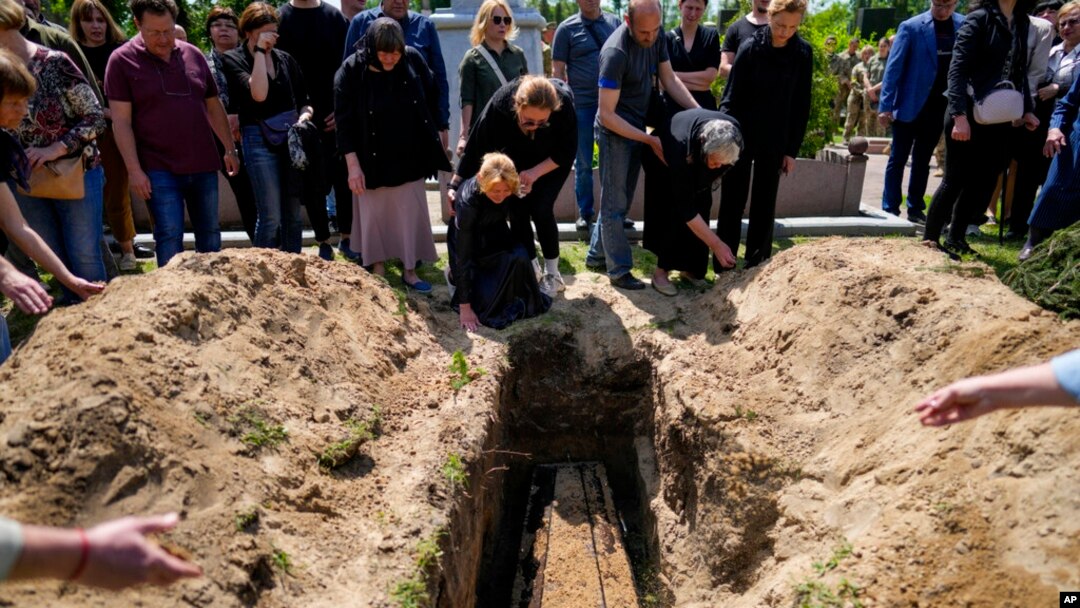 Relatives of Army Col. Oleksander Makhachek mourn during his funeral in Zhytomyr, Ukraine, June 3, 2022.