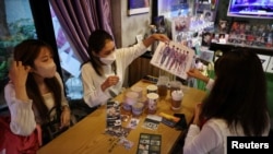 FILE - Japanese fans of K-pop boy band BTS, Hori, Tanaka Rina and Ohkubo share a moment at a cafe featuring BTS goods in Seoul, South Korea, June 15, 2022. 