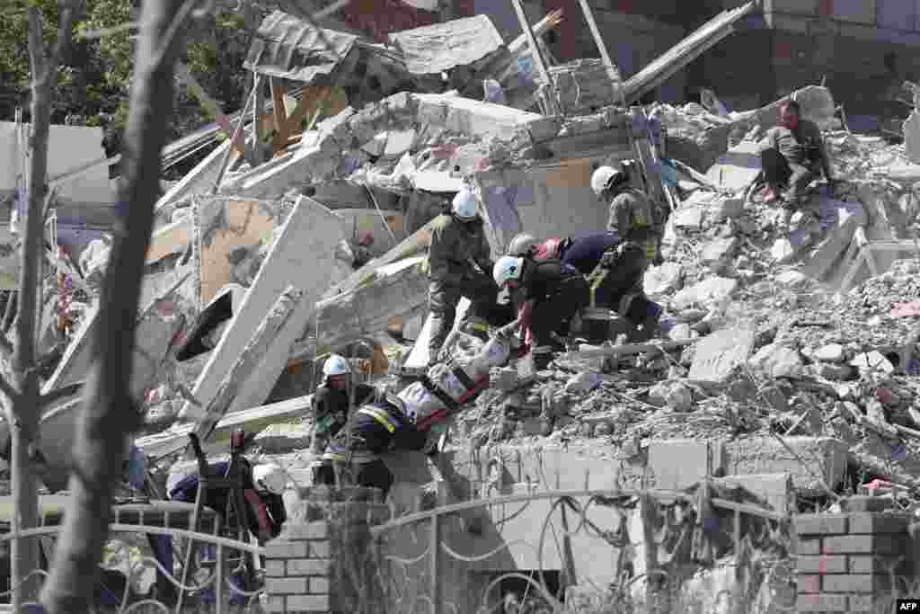Rescuers evacuate the body of a person from a destroyed building after being hit by a missile strike in the Ukrainian town of Sergiyvka , near Odessa, killing at least 18 people and injuring 30.