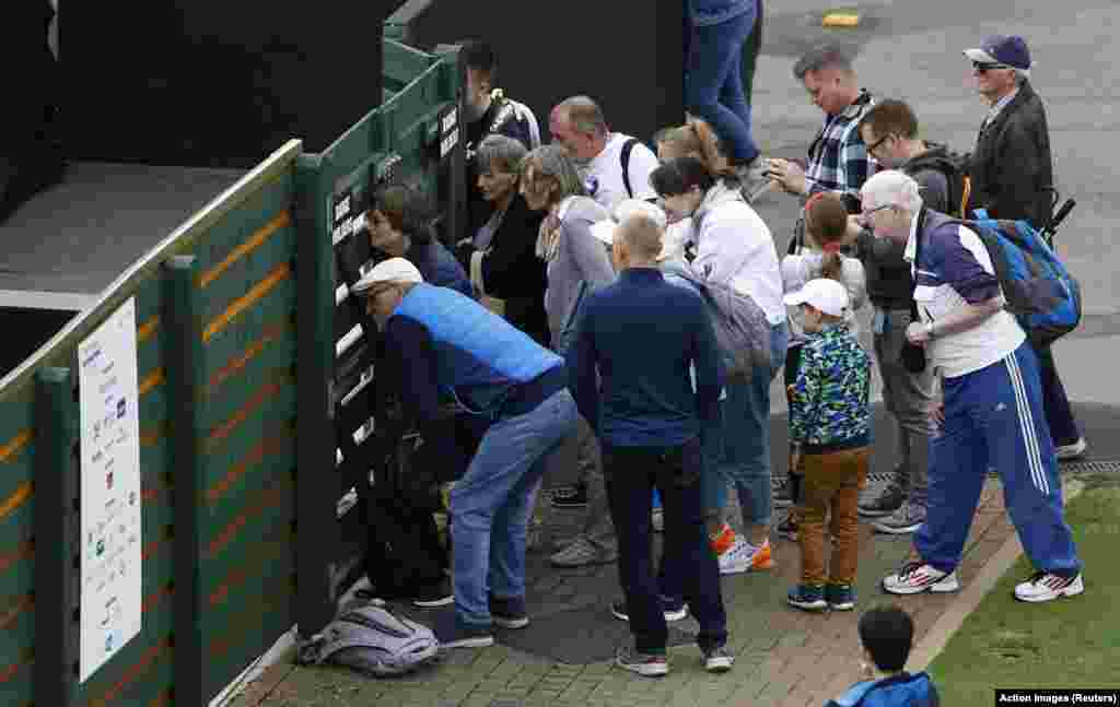 Fans look through the fence during the qualifying match of the Eastbourne international tennis tournament between Britain's Heather Watson and Ukraine's Lesia Tsurenko in Eastbourne, Britain.