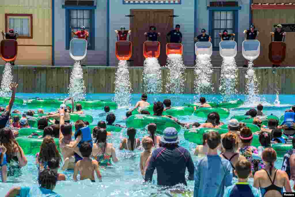 Employees dump ice into the pool at the Typhoon Texas Waterpark in Katy, Texas, June 26, 2022.