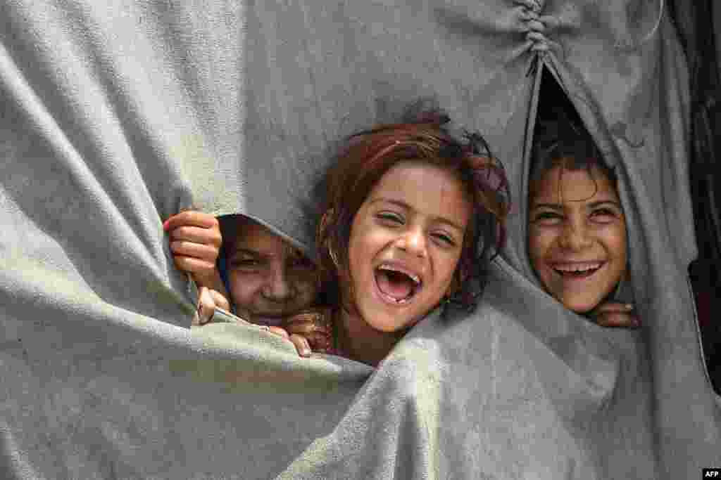Children of Afghan refugees living in Pakistan react to the camera from inside their makeshift tent on the outskirts of Lahore.