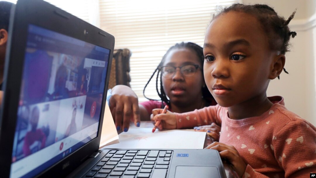 FILE — Lear Preston, 4, who attends Scott Joplin Elementary School, participates in her virtual classes as her mother, Brittany Preston, background, assists at their residence in Chicago's South Side, Feb. 10, 2021