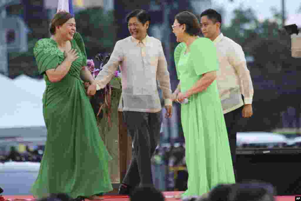 Vice President-elect Sara Duterte, left, the daughter of outgoing populist president of the Philippines, is greeted by incoming President Ferdinand "Bongbong" Marcos Jr. second from left, after oath-taking rites in her hometown in Davao city, southern Philippines.