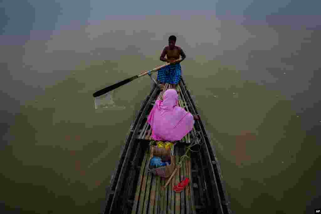 A man rows his boat to ferry a woman across an island in the river Brahmaputra on the outskirts of Gauhati, Assam state, India.