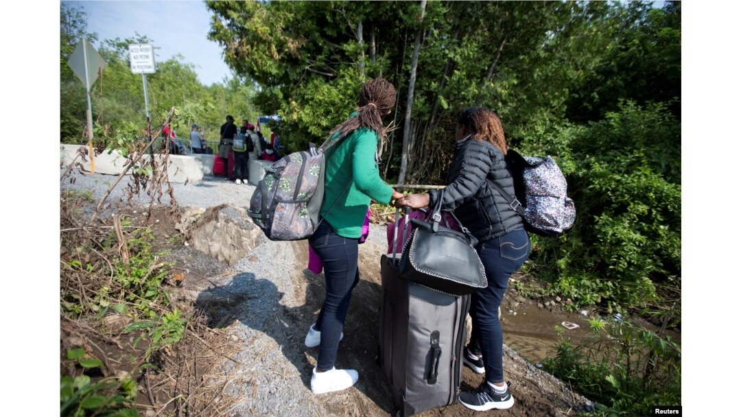 FILE - Women claiming to be from Burundi cross the U.S.-Canada border into Quebec from Champlain, New York, Aug. 3, 2017.