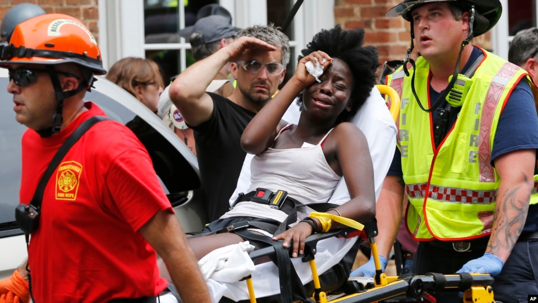 Rescue workers help an injured woman after a car ran into a large group of activists protesting a white nationalist demonstration in Charlottesville, Virginia, Saturday, Aug. 12, 2017. (AP Photo/Steve Helber)