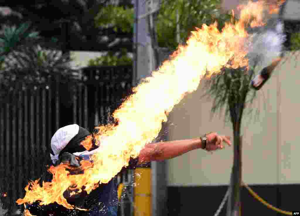 A student of the Autonomous National University of Honduras (UNAH) throws a Molotov cocktail at riot police during a protest demanding the resignation of Honduran President Juan Orlando Hernandez, in Tegucigalpa, Jan. 28, 2019, on the second day of protests.