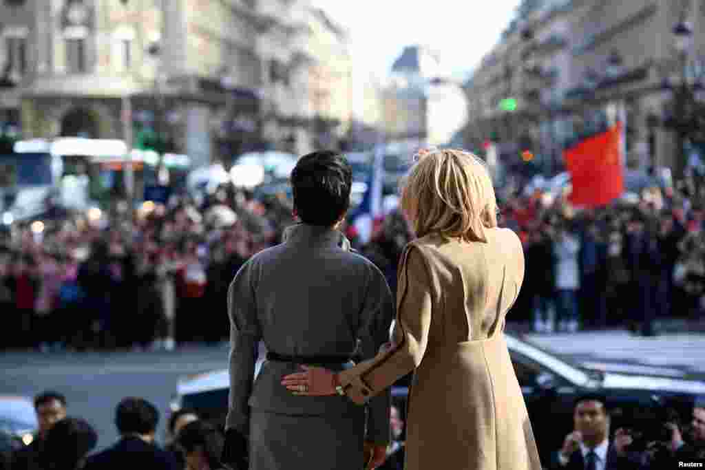 French president's wife Brigitte Macron (R) and Chinese president's wife Peng Liyuan wave to the crowd as they visit the Palais Garnier opera house in Paris, France.