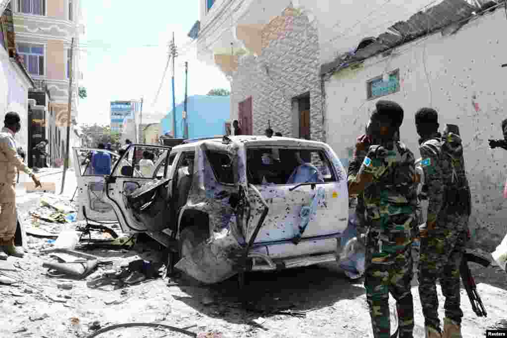 Somali security look at the wreckage of a vehicle at the scene of an explosion Mogadishu. Somalia's government spokesperson was wounded in the explosion at a road junction set off by a suicide bomber, police and the national news agency said.