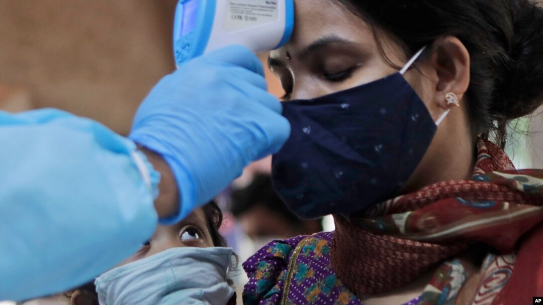 A child looks at his mother being screened for COVID-19 symptoms at an apartment complex in Mumbai, India, July 28, 2020.