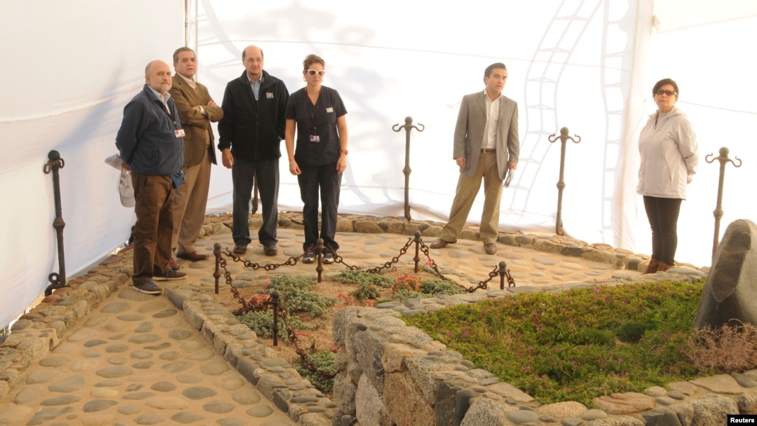 El juez chileno Mario Carroza y el director de servicios forenses inspeccionan la tumba de Pablo Neruda durante la exhumación de sus restos.
