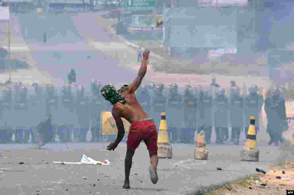 Demonstrators throw stones at Venezuelan Bolivarian National Guard members standing guard in the Venezuela-Brazil border, in Pacaraima, Roraima state, Brazil.