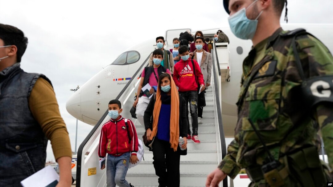 Afghan music students, faculty members and their families disembark from an airplane at Lisbon military airport, Dec. 13, 2021. 