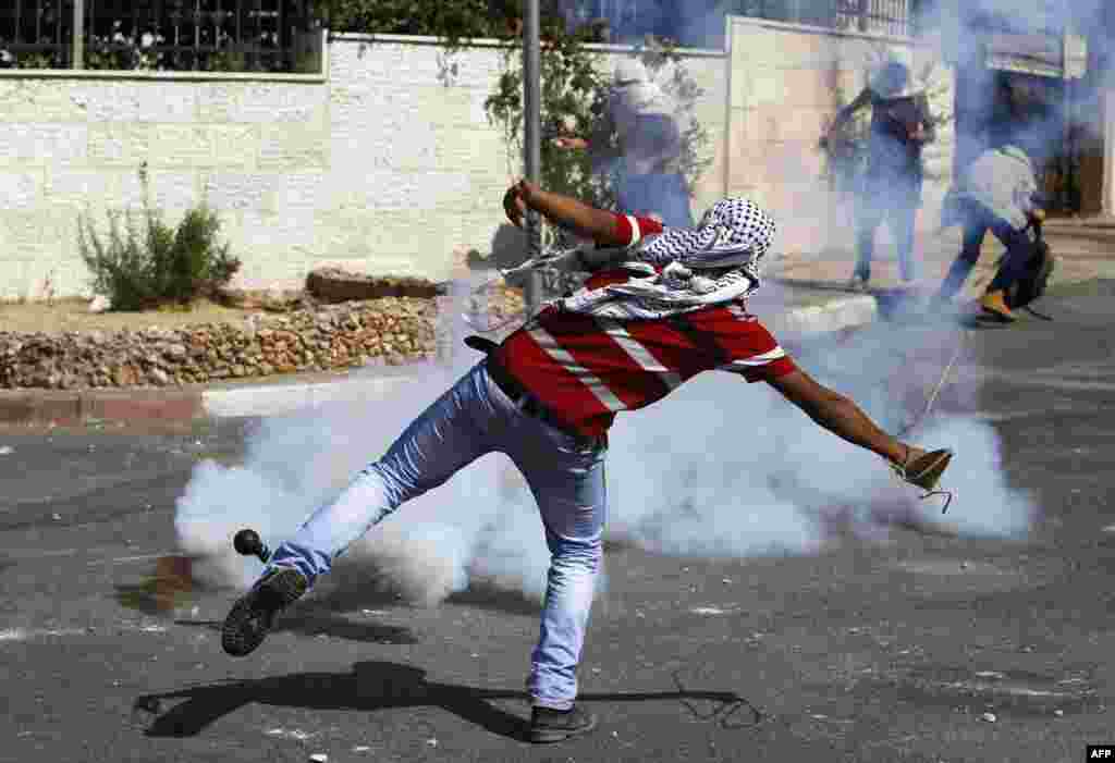 Palestinian protesters throw stones at Israeli soldiers, after the funeral of 22-year-old Palestinian Issa al-Qatari, at the Amari refugee camp near the West Bank city of Ramallah. 