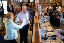 El presidente Joe Biden entrega helado a la senadora Tammy Baldwin, demócrata por Wisconsin, durante una parada en The Pearl Ice Cream Parlour, el 29 de junio de 2021, en La Crosse, Wisconsin.