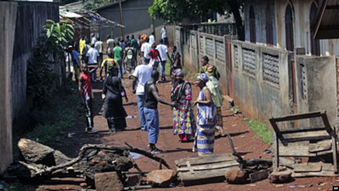 Residents of the mostly Peul suburb of Bambeto, Conakry, walk back to their homes behind barricades they set after a shooting incident, 17 Nov 2010