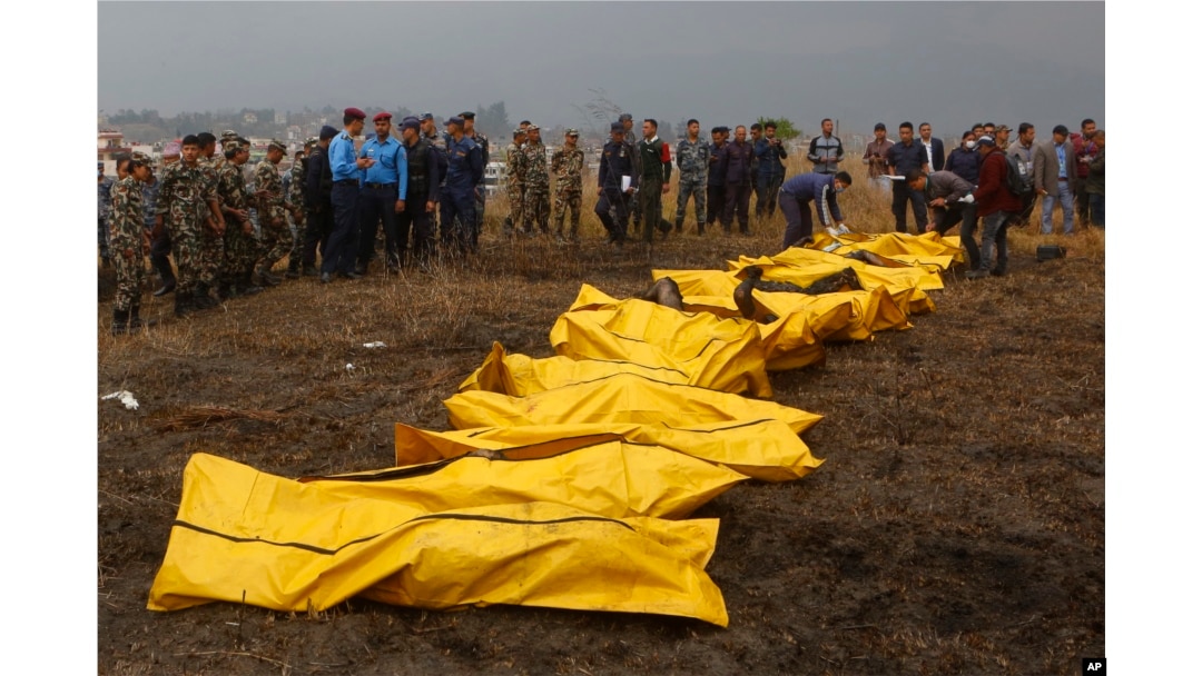 Nepalese rescuers attend to bodies of victims after a passenger plane from Bangladesh crashed at the airport in Kathmandu, Nepal, March 12, 2018.