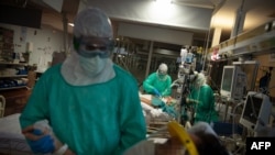FILE - Healthcare workers attend to COVID-19 coronavirus patients at the Intensive Unit Care of the Povisa Hospital in Vigo, northwestern Spain, on April 16, 2020. 