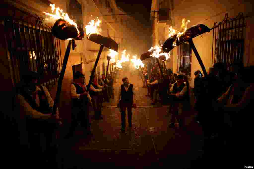 Villagers hold torches to represent light and vision during the Divina Pastora procession, as part of a festival to honor the Virgin of Los Rondeles, on the eve of St. Lucia's Day, in Casarabonela, near Malaga, southern Spain, Dec. 12, 2017.
