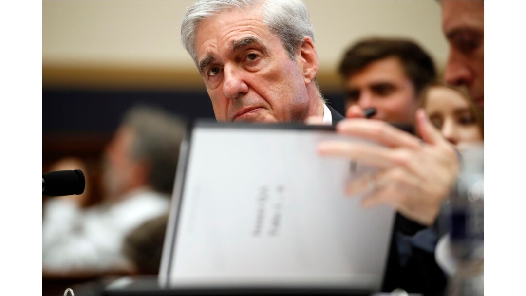 FILE - Former special counsel Robert Mueller checks pages in the report as he testifies before the House Judiciary Committee hearing on his report on Russian election interference, on Capitol Hill, July 24, 2019.