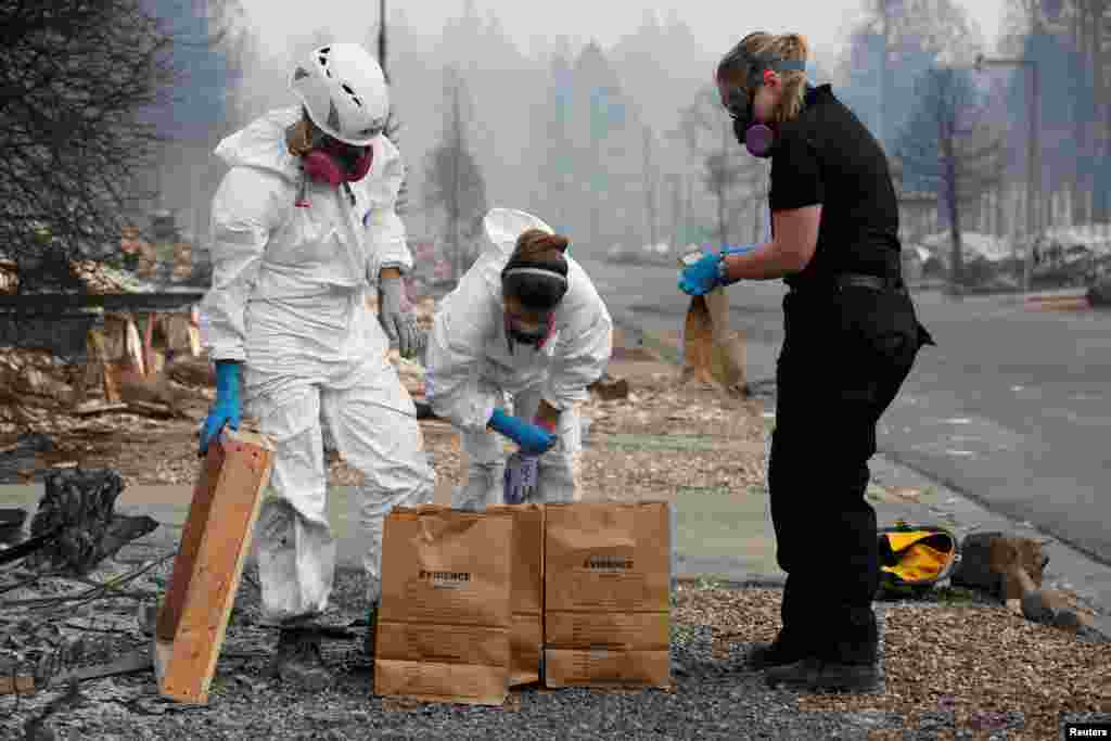 (L-R) Forensic anthropologists Kyra Stull and Tatiana Vlemincq work with San Mateo County Deputy Coroner Elizabeth Ortiz to recover human remains from a trailer home destroyed by the Camp Fire in Paradise, California, Nov. 17, 2018.