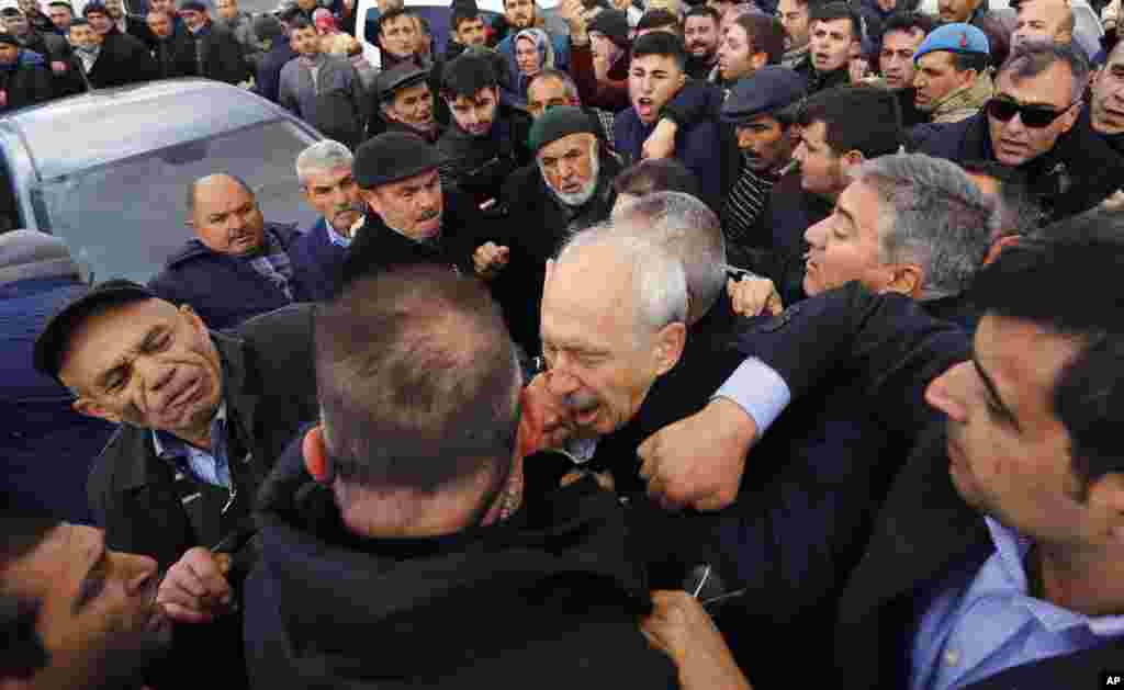 A man punches Kemal Kilicdaroglu, the leader of Turkey's main opposition Republican People's Party, during the funeral of a soldier who was slain during clashes with Kurdish rebels at Iraq border, outside Ankara, Turkey.