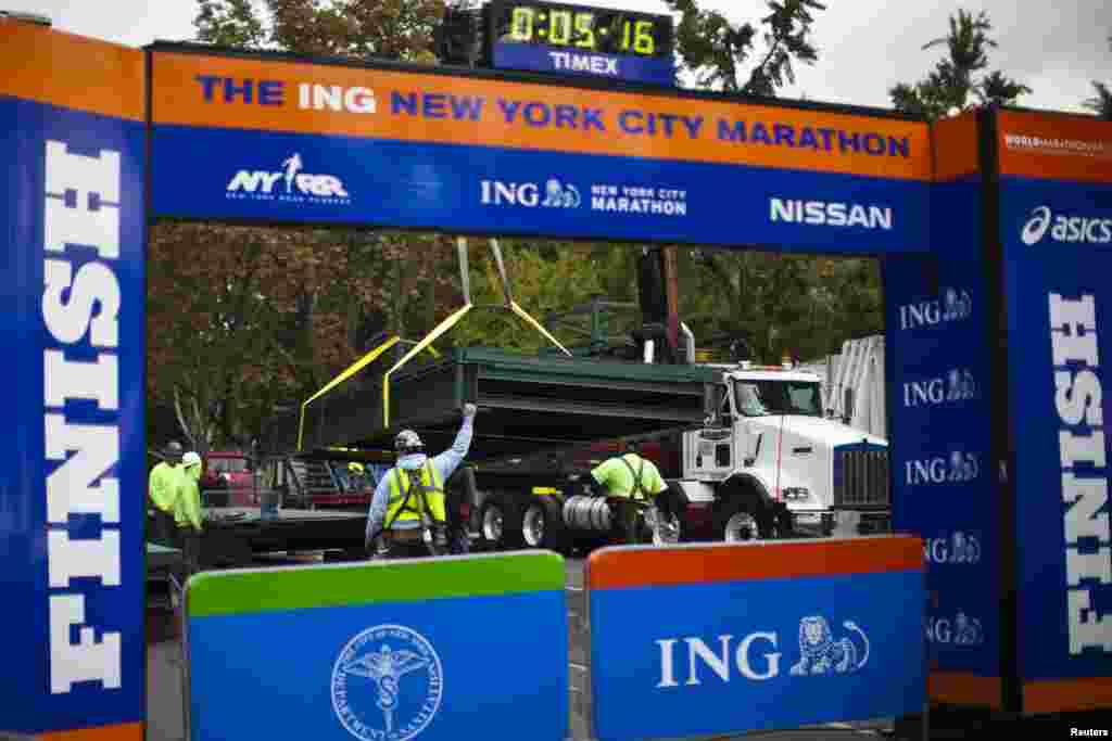 Workers install a platform after the ceremonial painting of the New York City Marathon blue line at Central Park, New York, Oct. 30, 2013.