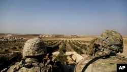 American troops look out toward the border with Turkey from a small outpost near the town of Manbij, northern Syria, Feb. 7, 2018. 