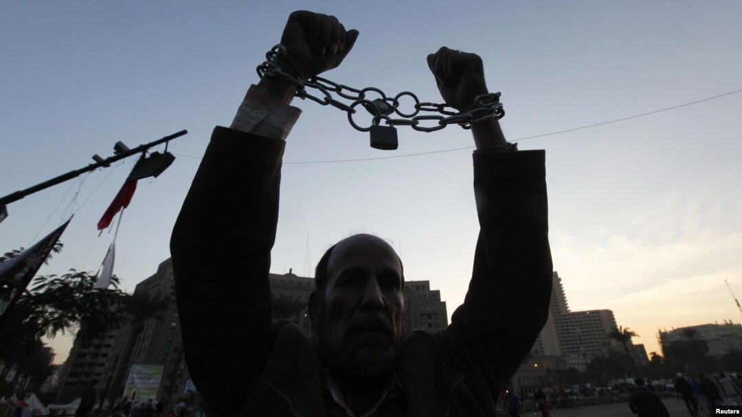 A man holds up his chained hands as he protests against Egypt's President Mohamed Morsi at Tahrir Square in Cairo, Egypt, December 18, 2012.