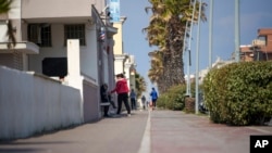 People walk along the promenade in the seaside town of Ostia, near Rome, April 13, 2020.