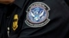 Таможенник с нашивкой Агентства таможенной и пограничной охраны США, в Международном аэропорту имени Джона Ф. Кеннеди в Нью-Йорке, 27 октября 2017 года,