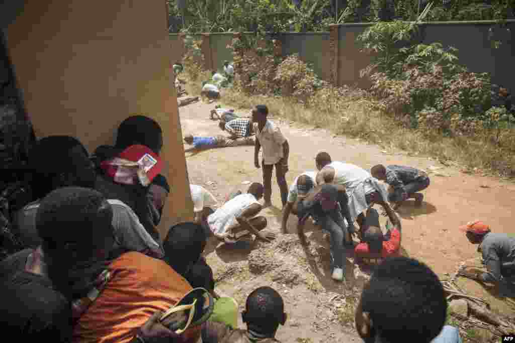 Protesters take cover outside the offices of the electoral commission in Beni during a demonstration against the postponement of elections in Beni territory and the city of Butembo, Democratic Republic of Congo.