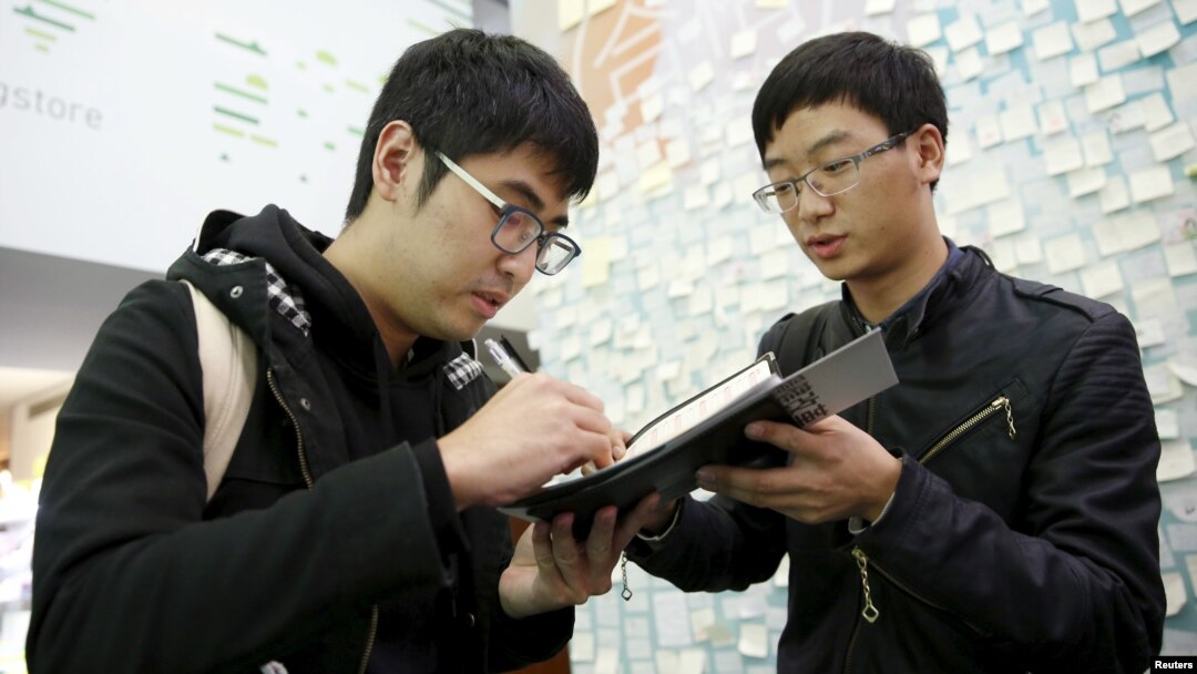 FILE - Student leader Alex Chow, (L) who took part in Hong Kong's Occupy Central or the so-called "Umbrella" movement, signs an autograph for a student from mainland China at Taiwan's Democratic Progressive Party (DPP) headquarters in Taipei, Taiwan, Jan. 14, 2016.