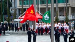 In this photo released by Xinhua News Agency, policemen perform a flag-raising ceremony in Macao, Dec. 20, 2021, marking the 22nd anniversary of the former Portuguese colony's handover to Chinese rule. 