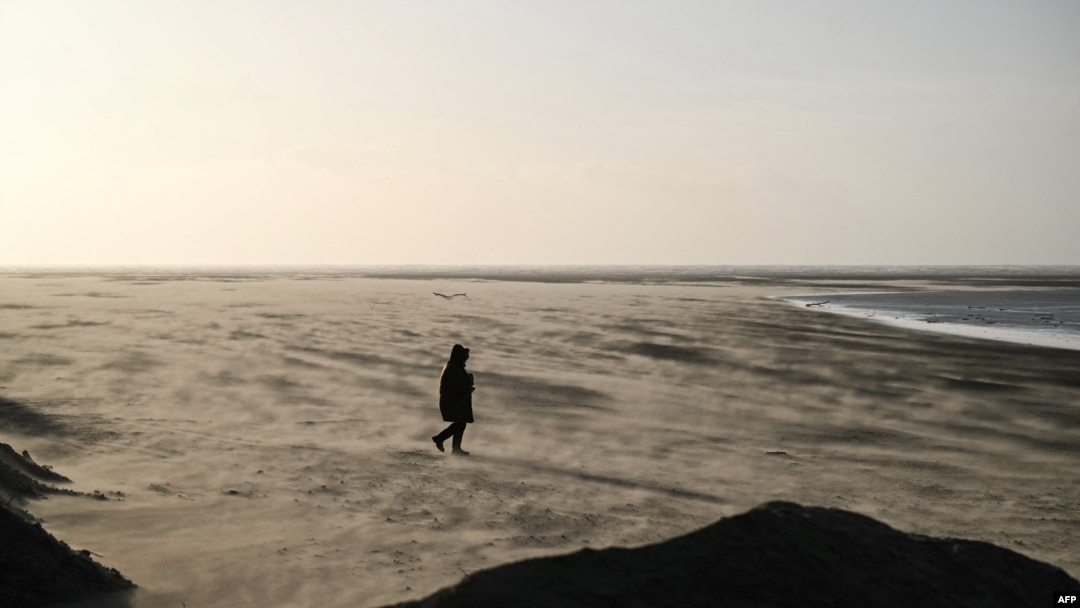 A person walks among the blows sand on St Annes beach in Lytham St Annes, near Blackpool, north-west England on Jan. 24, 2025, as storm Eowyn brings winds of 100 mph to the UK and Ireland. 