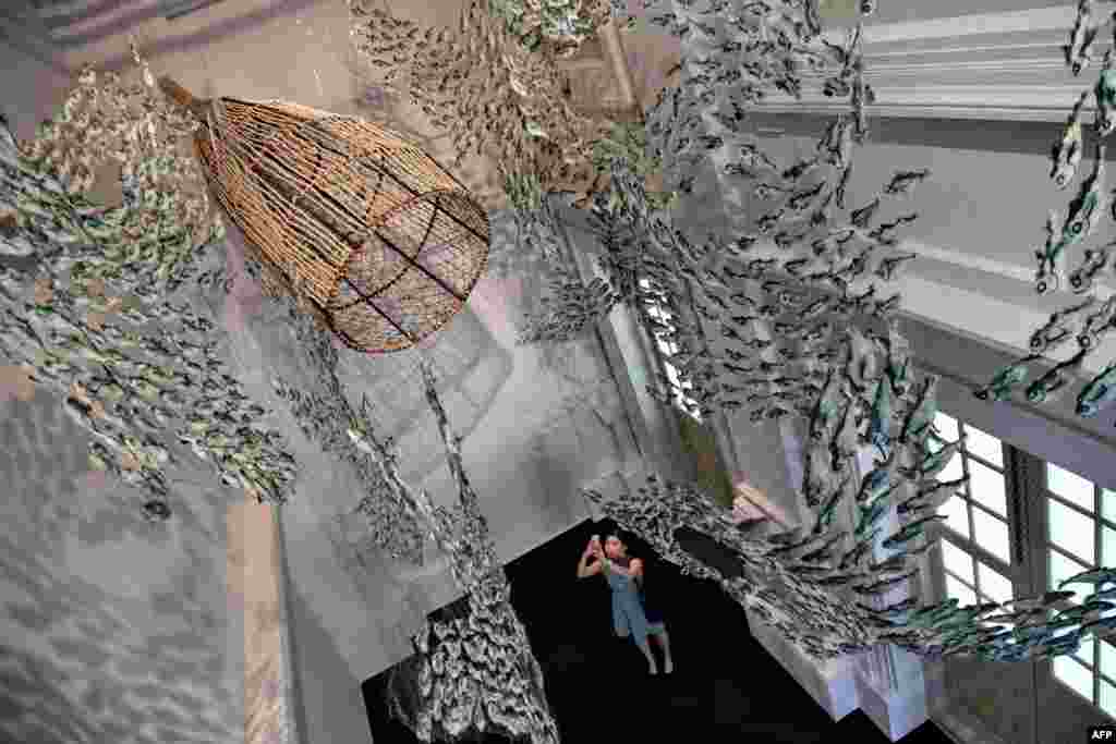 A woman takes a photograph of an art installation of marine life created from abandoned fishing nets by Erub Arts group artists from Australia's Darnley Island at the Asian Civilisations Museum in Singapore.