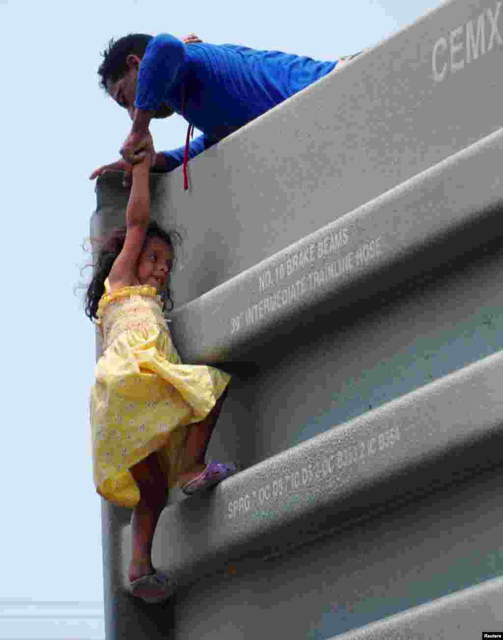 A man helps a girl to climb onto a boxcar as they join other Central American migrants (not pictured) in the freight train known as "The Beast" in Ixtepec, Mexico, during their journey toward the United States, April 30, 2019.