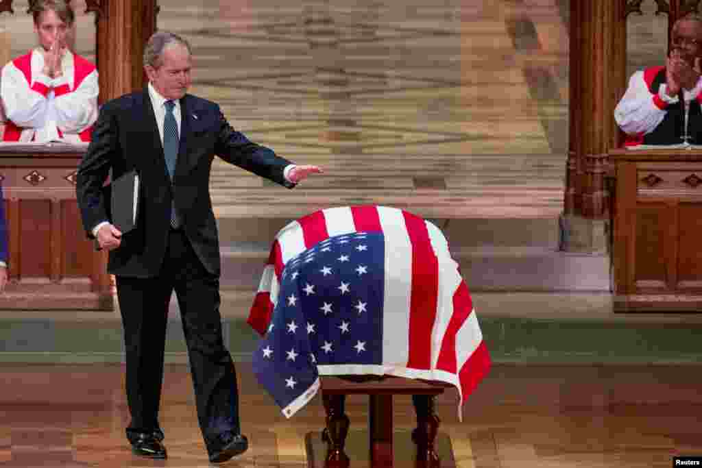 An emotional former President George W. Bush, the 43rd president of the U.S., touches the flag-draped casket of his father, the nation's 41st president, George H.W. Bush, after speaking during his state funeral at the National Cathedral, in Washington.