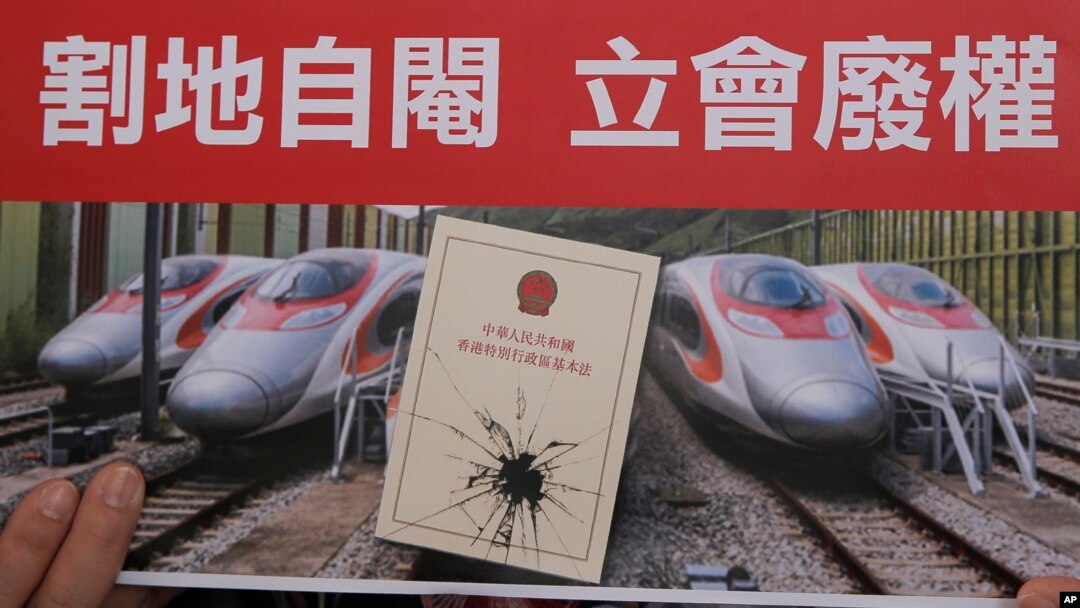 FILE - An activist holds a card at a protest near the West Kowloon terminus of the Guangzhou-Shenzhen-Hong Kong Express Rail Link, Dec. 28, 2017. Some Hong Kong legal scholars say the "co-location arrangement," is unconstitutional.