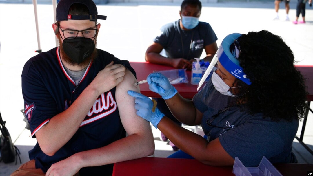 Chandler Millard, left, of Alexandria, Va., receives a Johnson & Johnson vaccine at a COVID-19 vaccination clinic hosted by the Washington Nationals outside of Nationals Park before a baseball game against the Colorado Rockies, Sept. 18, 2021. (AP Photo/Nick Wass)