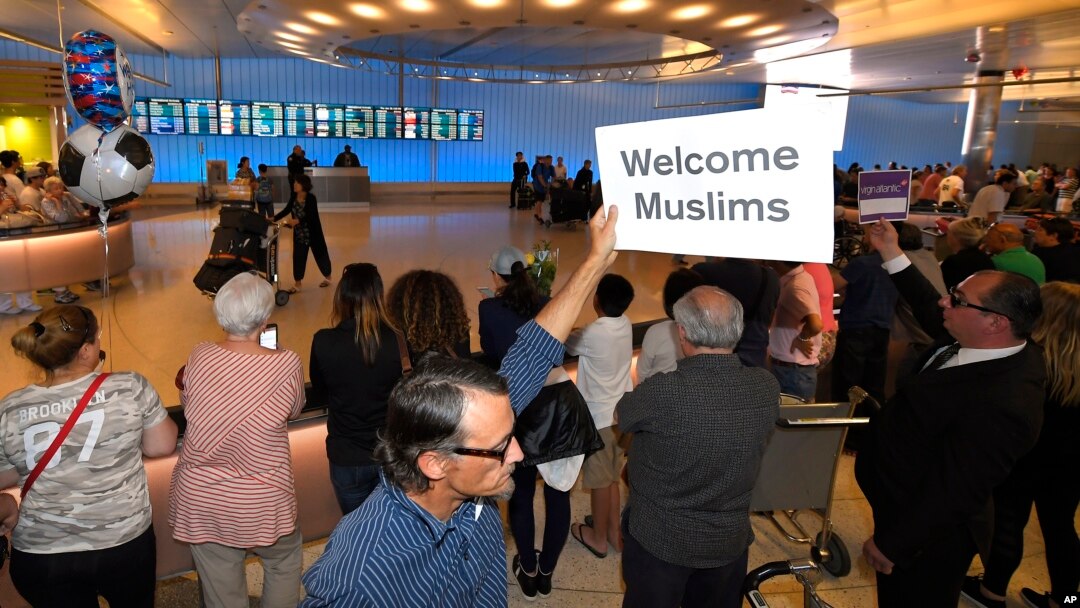 Un hombre muestra un cartel de bienvenida a los musulmanes en el Aeropuerto Internacional Tom Bradley de Los Ángeles, el jueves 29 de junio.