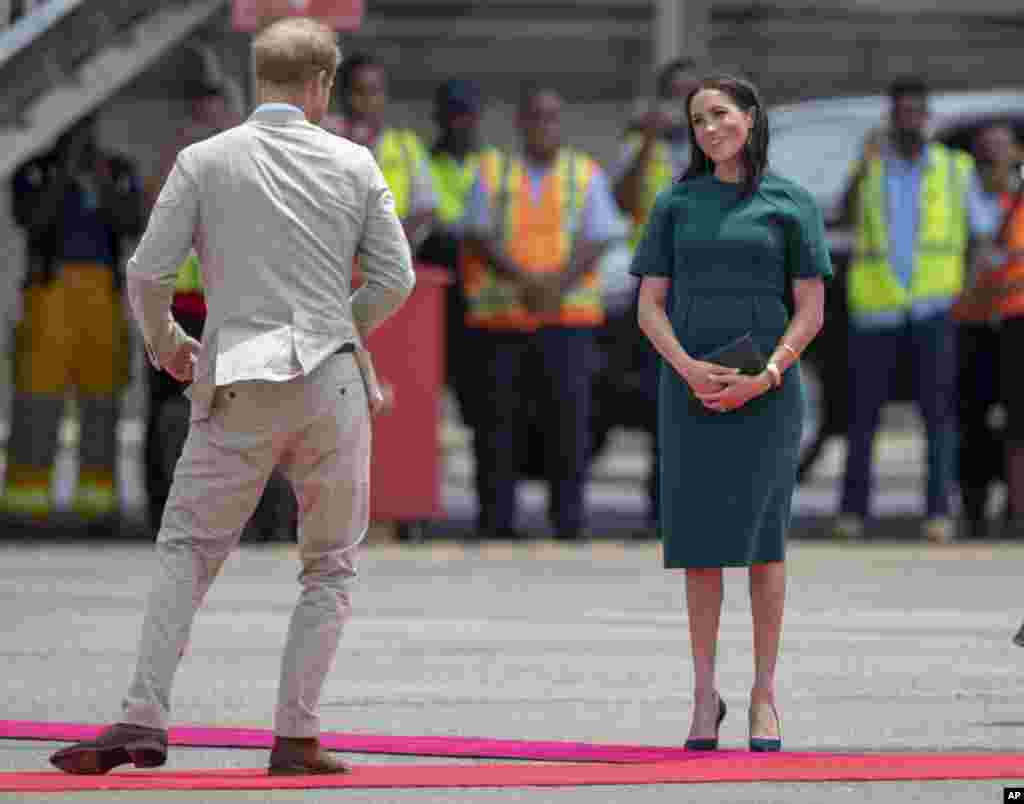 Britain's Prince Harry and Meghan, Duchess of Sussex, react before boarding their flight in Nadi, Fiji.
