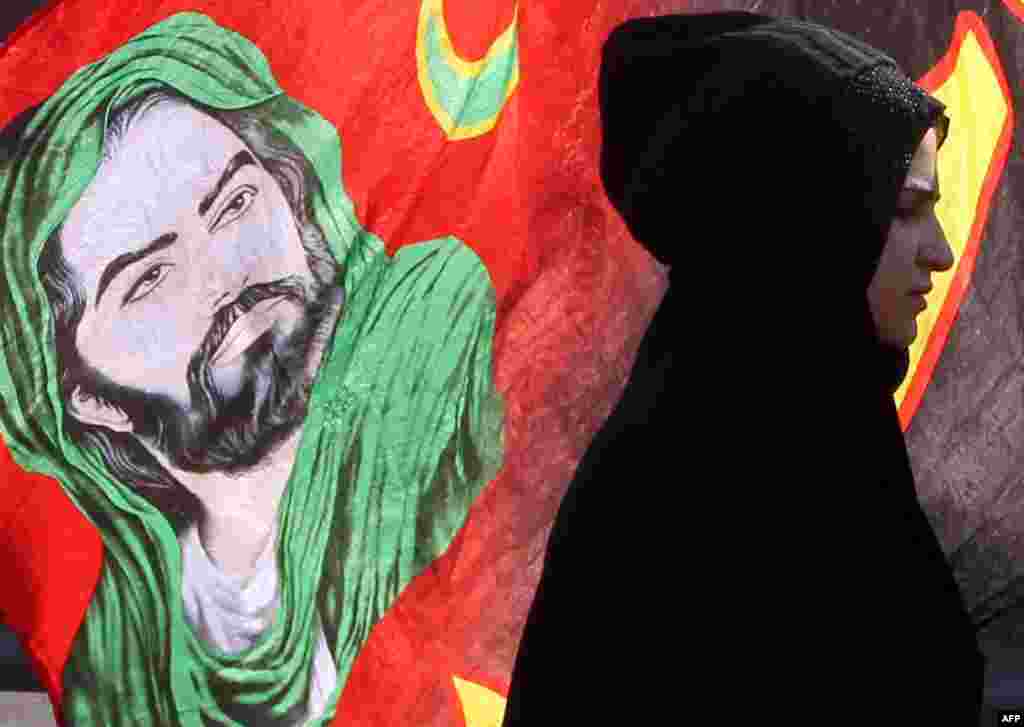 An Iraqi Shiite Muslim pilgrim walks past a banner with an image of Imam Hussein along the main highway that links Baghdad with the central shrine city of Karbala, to take part in the Arbaeen religious festival. The festival marks the 40th day after Ashura commemorating the 7th century killing of Prophet Mohammed's grandson.