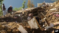 Pakistani villagers collect their belongings under the rubble of their homes destroyed from an earthquake in Shangla in Swat valley, Pakistan, Oct. 28, 2015. 