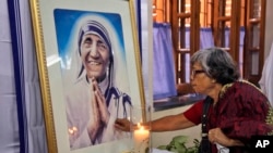 Una mujer india católica reza mientras toca un retrato de la madre Teresa en sede de Misioneras de la Caridad en Calcuta, India.