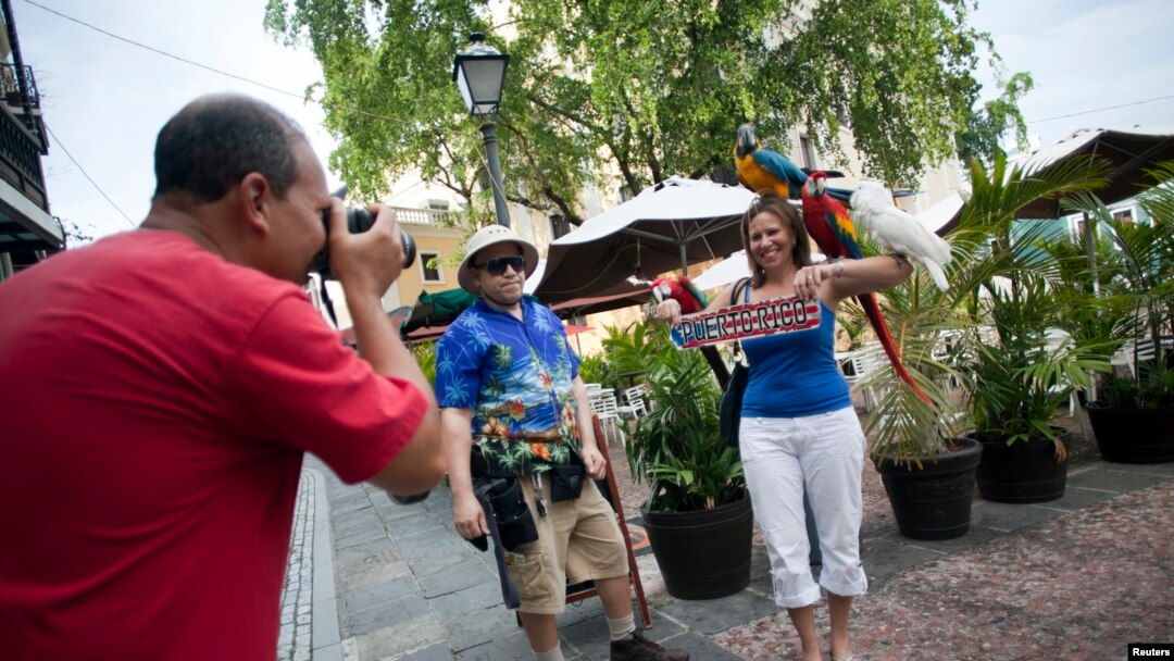 FILE - Tourist Cindy Huyzen poses for her husband, Michael Huyzen, while visiting San Juan, Puerto Rico, July 19, 2015.