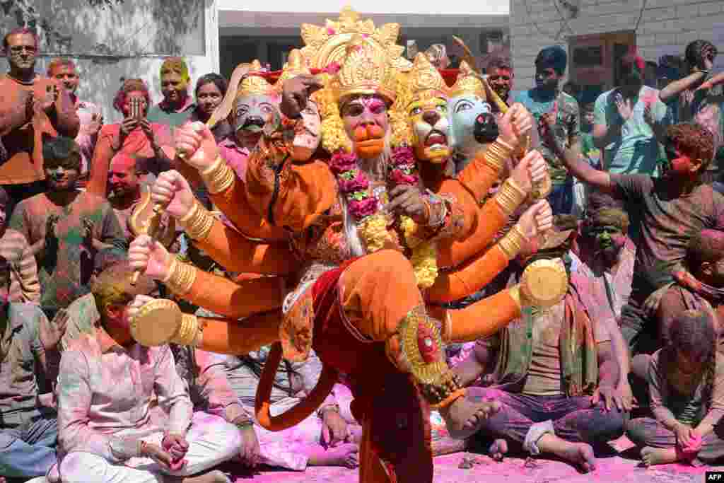 An Indian artist dressed as Lord Hanuman performs traditional folk dance during Holi festival celebrations at a temple in Amritsar.